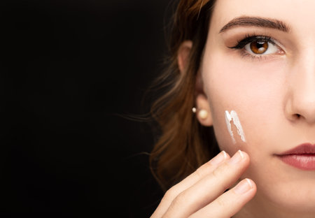 Studio shot of a young woman aplying face cream. Beautiful young woman.