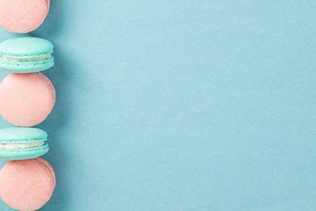 Blue and pink macarons on a blue background with copy space. French dessert.の写真素材