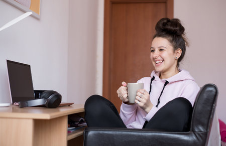 Young girl drinking coffee while studying. Girl laughing.