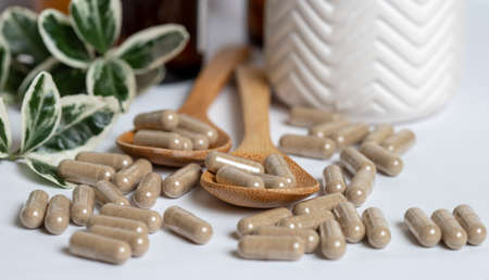 Vitamine capsules on a wooden spoon, on a white background.の写真素材