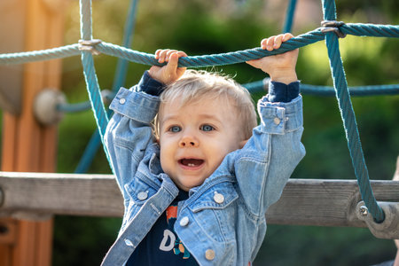 Little blond haired boy playing on the playground. Happy boy.