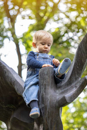 Little blond haired boy sitting in the nature and laughing.の写真素材