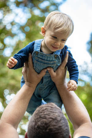 Little blond haired boy sitting in the nature and laughing.の写真素材