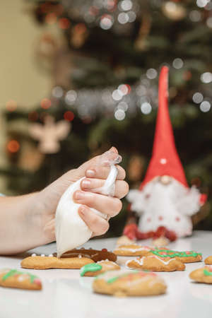 Unrecognizable woman decorating gingerbread in the kitchen. Christmas season.の写真素材