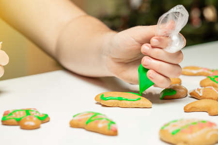 Unrecognizable woman decorating gingerbread in the kitchen. Christmas season.の写真素材