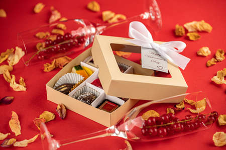 Valentine chocolate candies, gift box and red ribbon on a red background.の写真素材