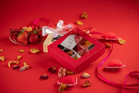 Valentine chocolate candies, gift box and red ribbon on a red background.の写真素材