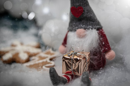 Little christmas gnome sitting in the snow, surrounded with christmas decoration.の写真素材