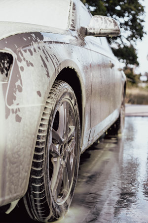 A woman washing her car. A young girl taking care of her car.