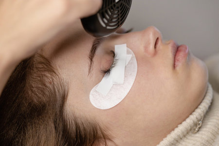 Eyelash Extension Procedure. Woman making eylash extensions for a girl.の写真素材