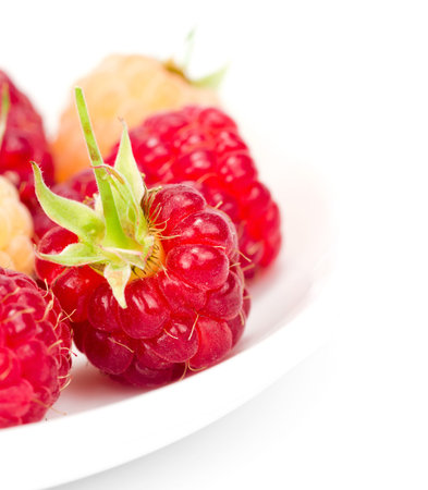 plateful of fresh raspberries on white 