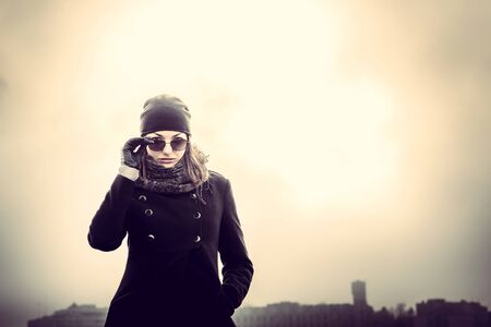 Girl in the sunglasses on the roof of high buildingの写真素材