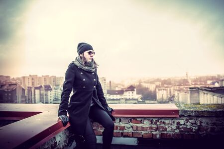 Girl in the sunglasses on the roof of high buildingの写真素材