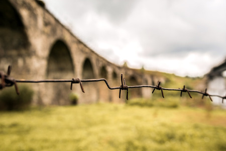 Barbed wire with old railway bridge in Carpathian mountains on backgroundの写真素材
