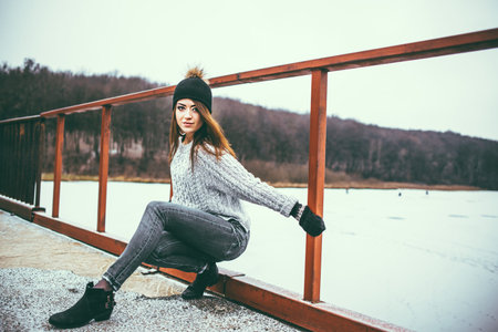 Young pretty girl on the bridge with forest and lake on backgroundの写真素材