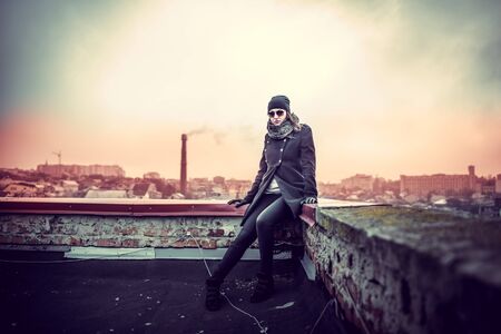 Girl in the sunglasses on the roof of high buildingの写真素材