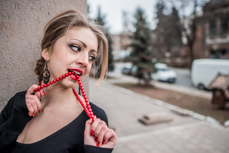 Young pretty sexy lady in black dress outdoor near old building with red lipsの写真素材