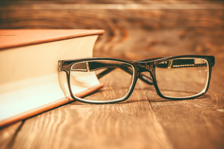 Old fashioned vintage book with glasses on wooden backgroundの写真素材
