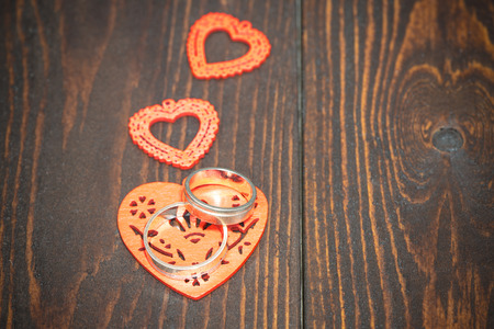 Red  hearts with wedding rings on warm wooden backgroundの写真素材