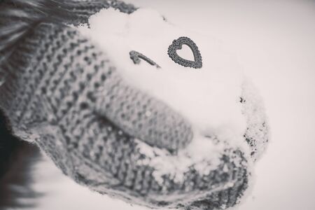 wooden hearts in the hands with snow on backgroundの写真素材