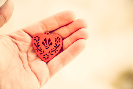 Red wooden heart in the hand on warm background