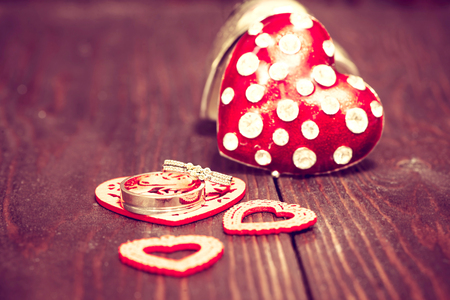 Red  hearts with wedding rings on warm wooden backgroundの写真素材