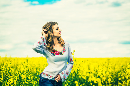 One pretty girl walking in the yellow field in embroidery shirtの写真素材