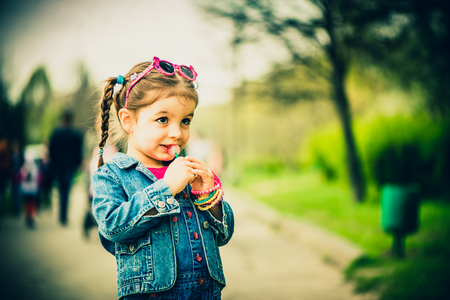 Little girl with lollipop outdoor in the parkの写真素材