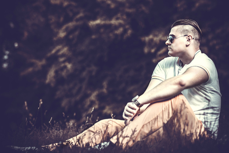 Brutal man sitting on the ground outdoor in sunglassesの写真素材