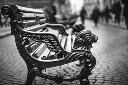 Vintage bench on the street with people silhouettes on backgroundの写真素材