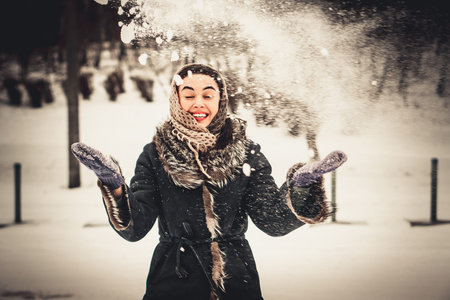 Happy girl outdoor throwing snow up in the air