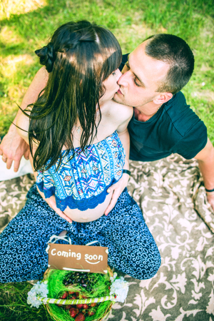 Pregnant women and her husband with basket of fruits in the parkの写真素材