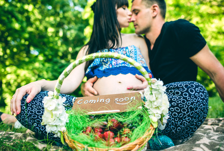 Pregnant women and her husband with basket of fruits in the parkの写真素材