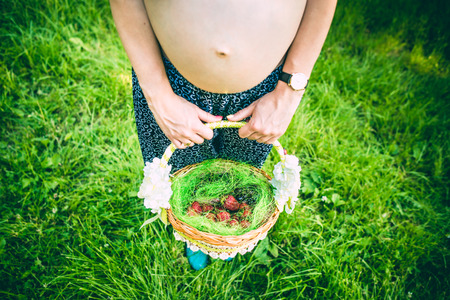 Pregnant woman outdoor in the park with fruits in basketの写真素材