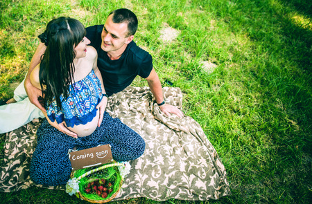 Pregnant women and her husband with basket of fruits in the parkの写真素材
