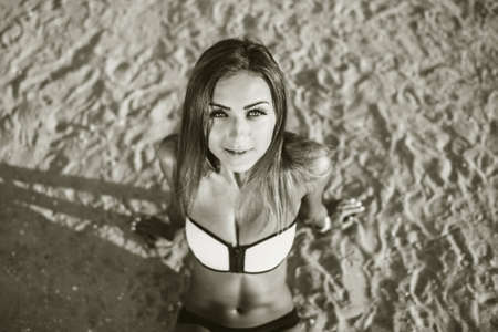 Sporty girl sitting on the beach in swimwearの写真素材