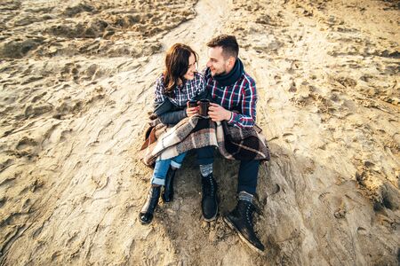 Pretty young couple sitting on the beachの写真素材