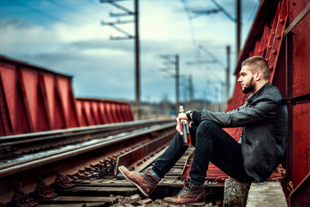 Young man with beard sitting on the railwayの写真素材