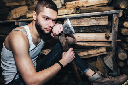 Man with ax in hands near firewood stockの写真素材