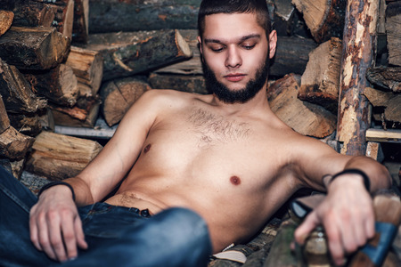 Man with beard rest near firewood stockの写真素材