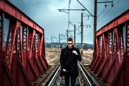 Young man with beard walking on the railwayの写真素材