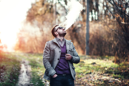 Man with beard smoking electronic sigarette outdoor