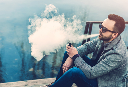 Man with beard smoking electronic sigarette outdoorの写真素材