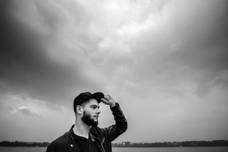 Man with beard sitting outdoor with lake behindの写真素材