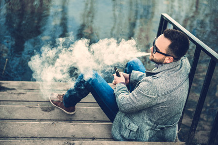 Man with beard smoking electronic sigarette outdoor
