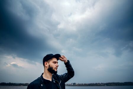 Man with beard sitting outdoor with lake behindの写真素材