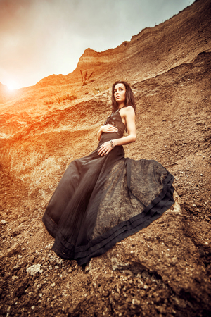 Pretty woman on the sand canyon in long black dressの写真素材