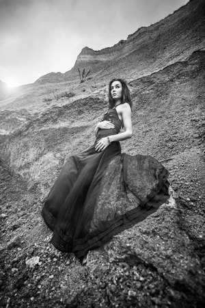 Pretty woman on the sand canyon in long black dressの写真素材