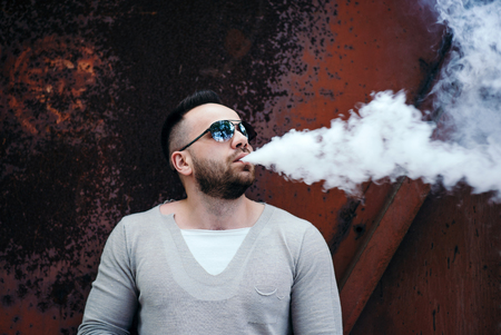Men with beard vaping outdoor in sunglassesの写真素材