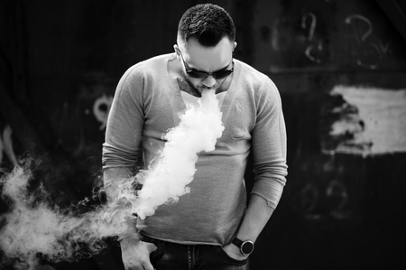 Men with beard vaping outdoor in sunglassesの写真素材